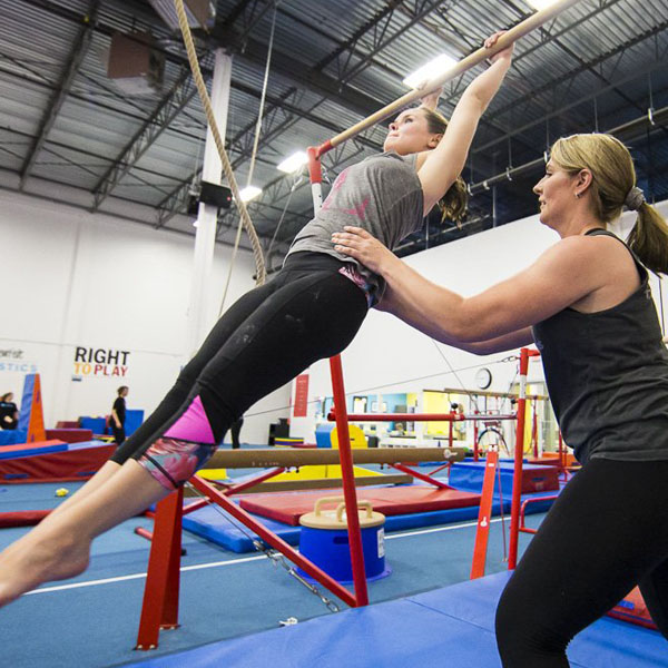 coach assiting an adult with shape while swinging on a bar
